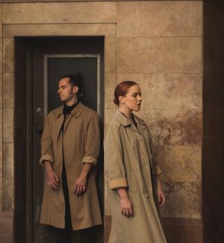 Man and woman standing infront of a door in trench coats