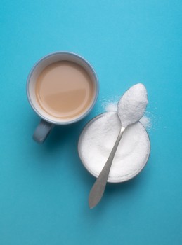 Stevia powder and tea cup on blue background