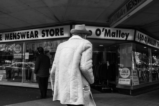 Man in a coat and hat in front of O'Malley's black and white