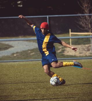 Football player with red beanie cap kicking ball - Sports Zone sunday league