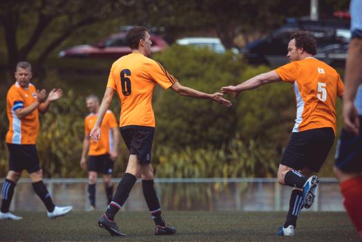 Teammates clap hands during football match - Sports Zone sunday league