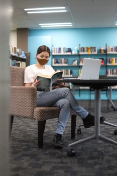 Girl reading fiction book in library