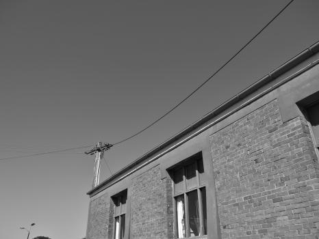 Brick building utility pole and power lines black and white