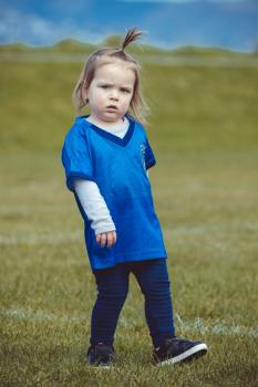 Little blonde girl in Italian football team jersey walking on grass - Little Dribblers