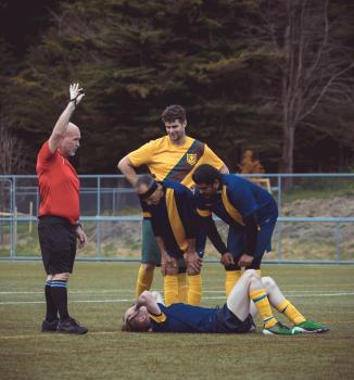 Referee and players stand by an injured player - Sports Zone sunday league