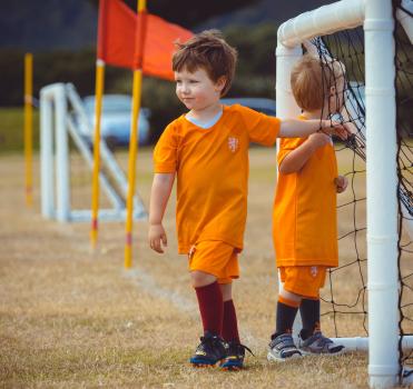 Two boys in Netherlands kit hanging at a football goal post - Little Dribblers