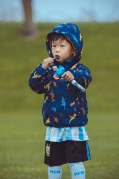 Child wearing a dinosaur hoodie eating lollypop
