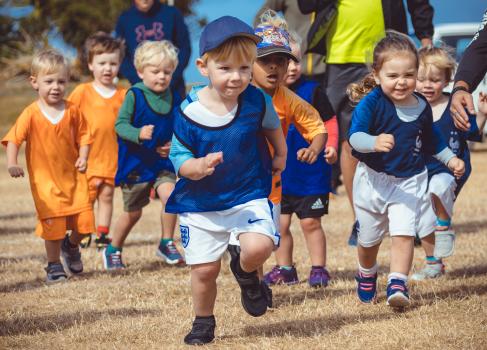 Multiple kids running after a football - Little Dribblers