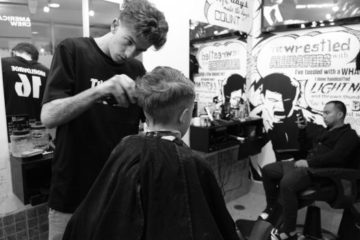 Barber giving a haircut to the boy black and white