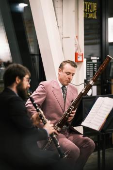 People playing clarinet and bassoon in pink suit at a concert