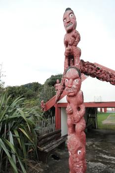 Maori red totem pole and flax plant