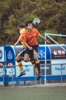 Player in orange shirt hitting a header at a football tournament
