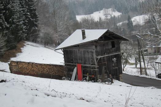 Snow covered wood shack and fire wood logs at the Swiss Alps
