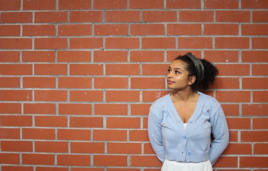 Girl in front of a brick wall looking up
