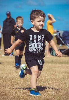 Little boy in black attire running on dry grass