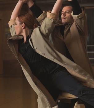 Male and female dancing in overcoats and black attire