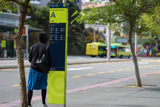Woman leaning on metlink station A board