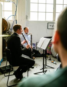 Musicians playing clarinet and bassoon next to paintings in a brewery