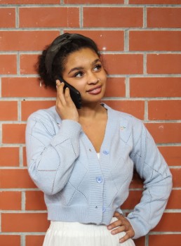 Girl talking on phone in front of brick wall