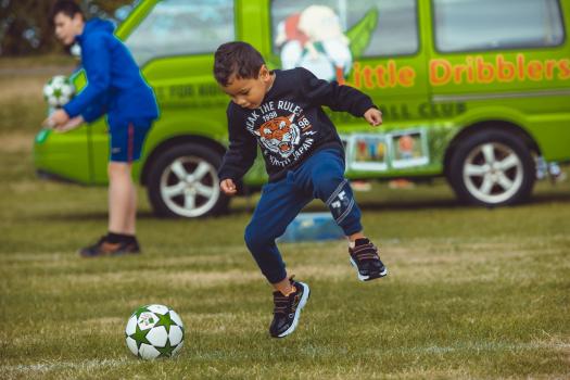 Boy jumping with a football at Little Dribblers ball game