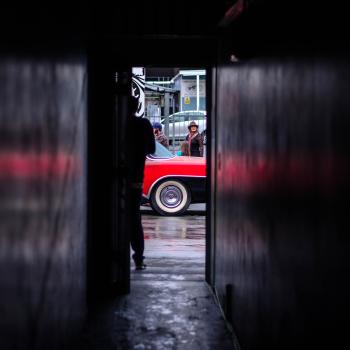 Red car parked outside a dark hallway in a building