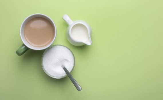 Stevia, tea cup and creamer on green surface