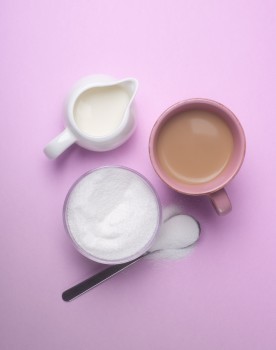 Tea, cream and stevia cups on pink background