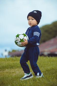 Little boy in blue jogging suit carrying a football - Little Dribblers