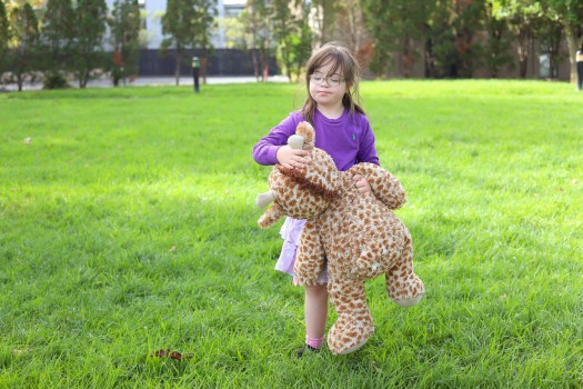 Child with Down syndrome caressing her toy