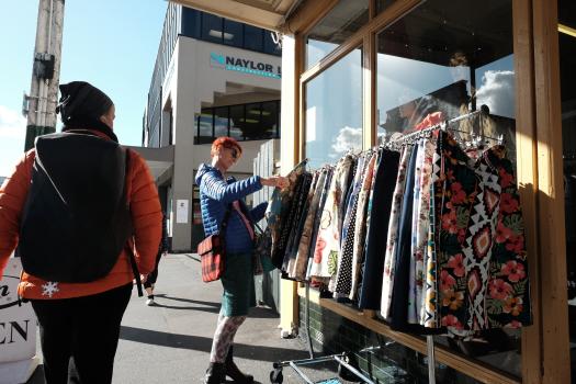 Red haired woman in blue jacket browsing through clothes outside