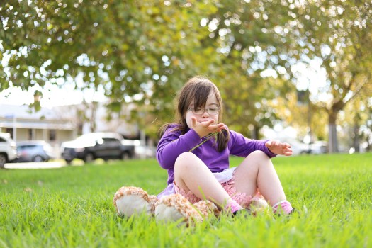 Girl with Down syndrome blowing away grass