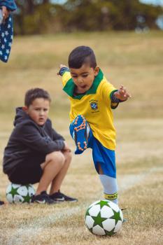 Boy in Brasil kit kicking football at Little Dribblers soccer game