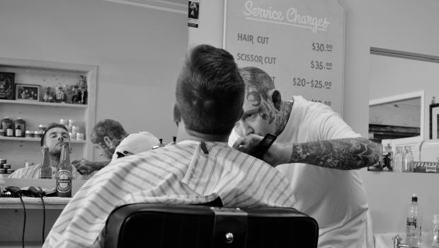 Customer getting a beard trim from a tattooed barber