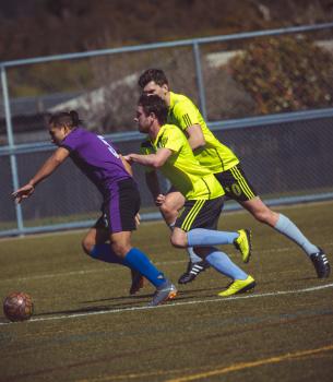 Two players in lime neon shirts try to tackle opponent - Sports Zone sunday league