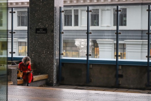 Lady in red overcoat sitting on a bench