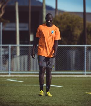 Tall dark skinned football player in orange Nike shirt
