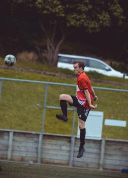 Player in red shirt kicks football midair - Sports Zone sunday league