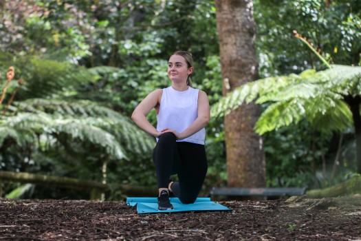 Woman exercising outdoors on a blue mat