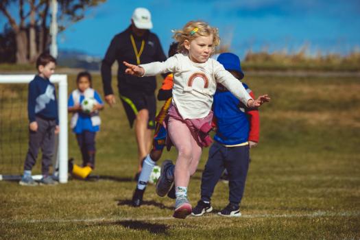 Little girl in pink leggings running at Little Dribblers soccer game