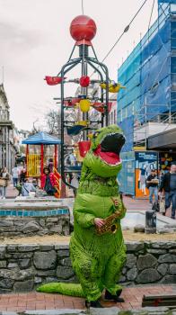 Person dressed as dinosaur holding musical instrument