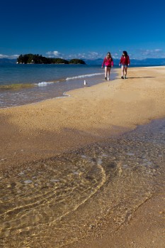 Two teenage girls walk Abel Tasman shore