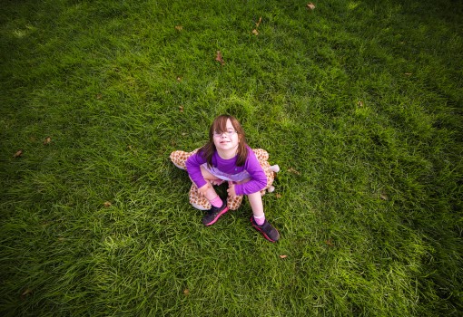 Girl with Down syndrome sitting on the grass