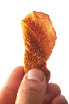 Fingers holding a brown chip