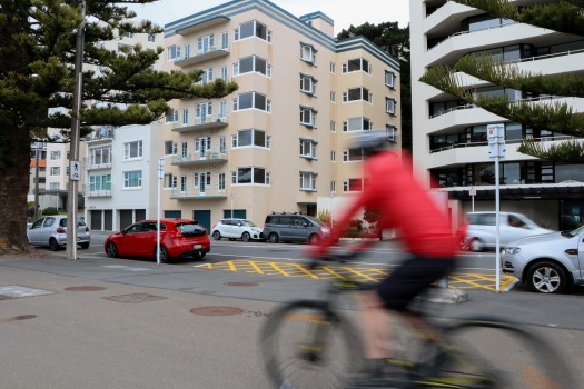 Cyclist passing by tall apartment buildings