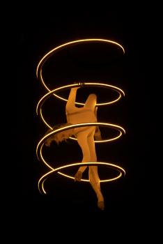 Woman performing acrobatics with a glowing spiral structure