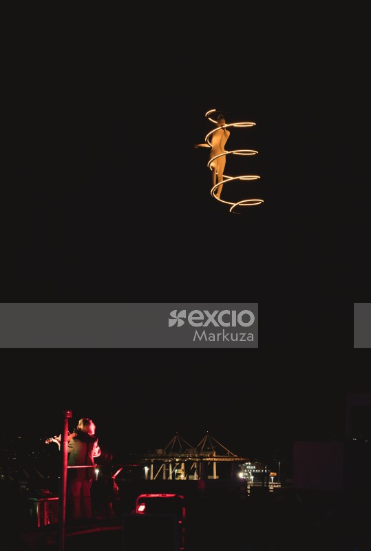 Acrobat on a higher ground with lighting filament and a violinist performing