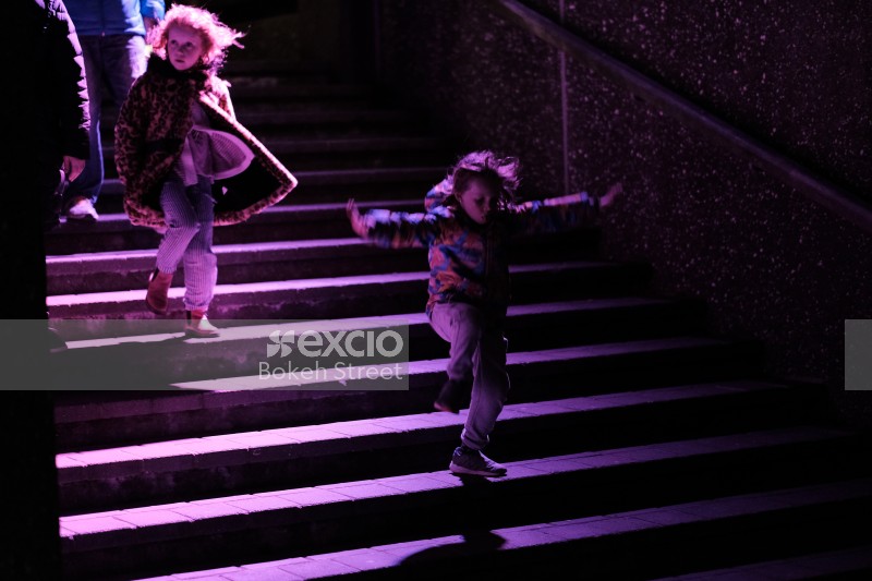 Children descending on purple lit steps