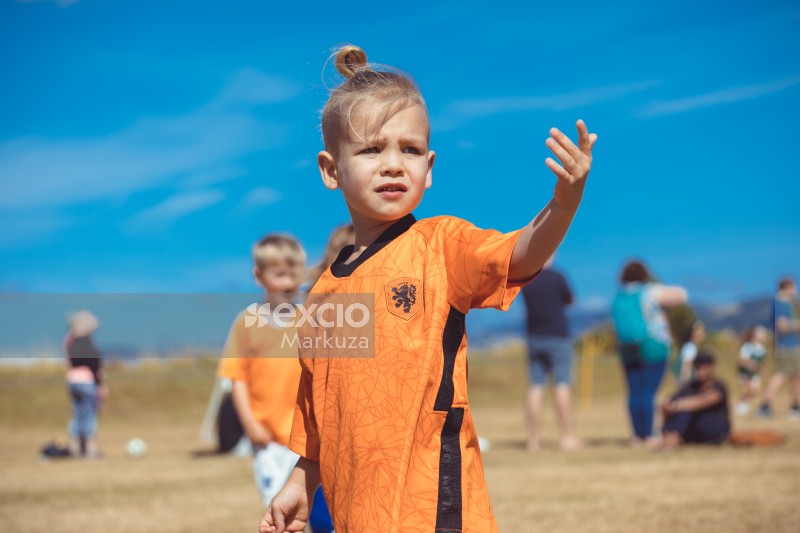 Little girl in orange kit and hairbun at Little Dribblers game event