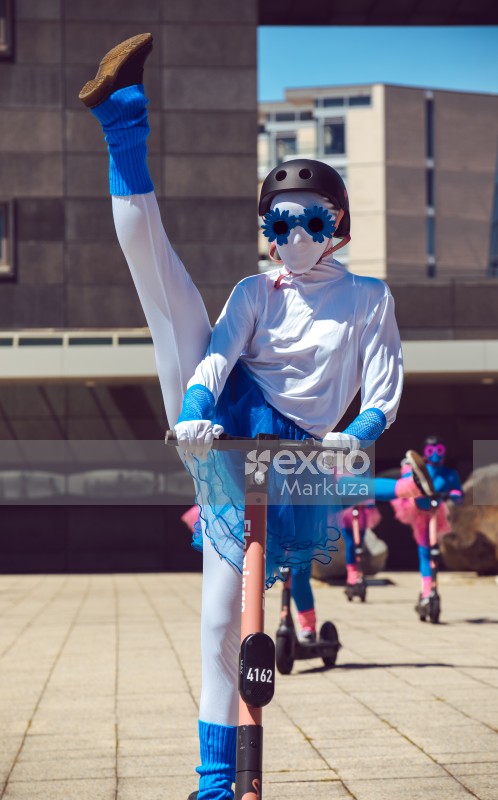 Ballet performer in blue socks raising leg on a scooter