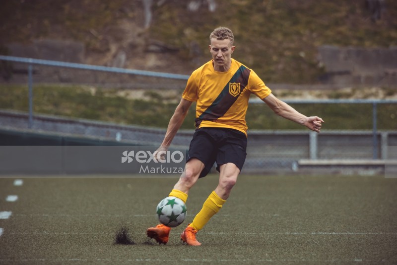 Sportsman in yellow shirt and orange cleats kicks football - Sports Zone sunday league